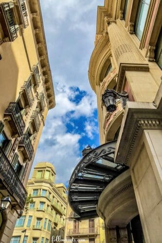 This imagge features an upward view of gothic style architectural buildings in Barcelona for the blog post titled Must See Places in Barcelona. Photo by Lisa Soots